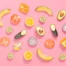 A collection of fruits and vegetables in compostable cling wrap on a pink background.