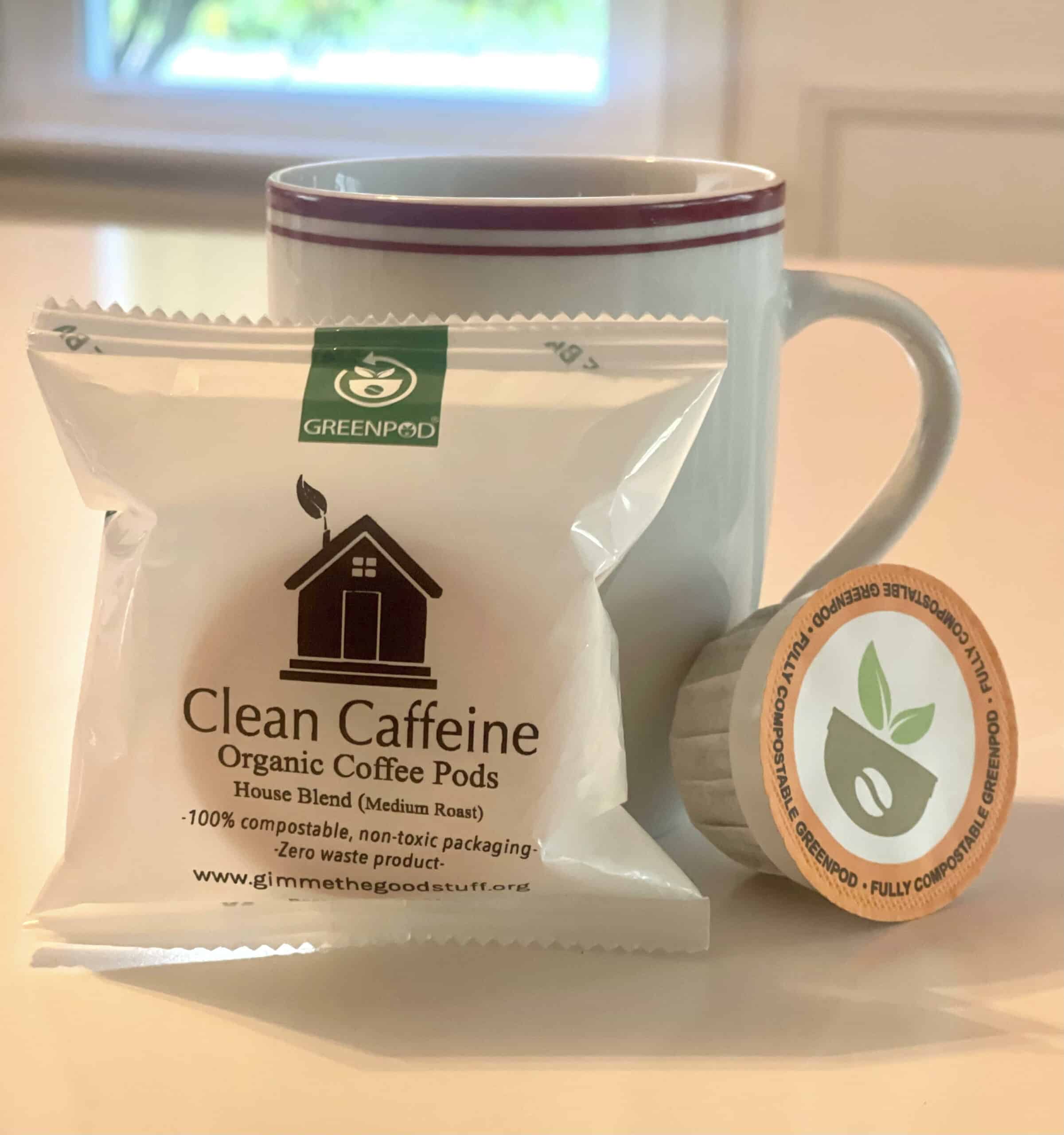An image of a coffee cup behind a compostable K cup with organic coffee.