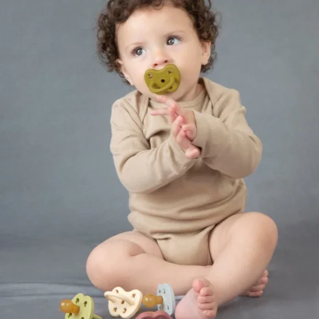 A baby sitting with a collection and using Hevea Natural Rubber Pacifiers from Gimme the Good Stuff 001