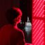 A man sitting in front of a red light therapy panel.