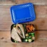 LunchBots Large Bento Trio Blue Dots sitting on a wooden table and filled with vegetables and a sandwich.
