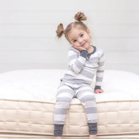 A photo of a young girl sitting on a Naturepedic Verse Organic Kids Mattress from Gimme the Good Stuff 008