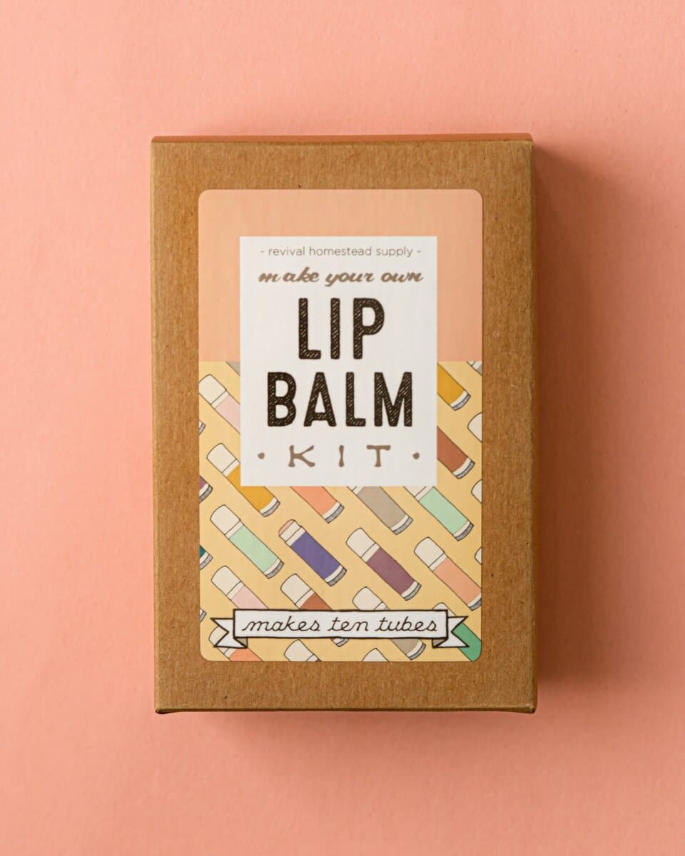 A cardboard box for making your own all natural lip balm on a pink background.
