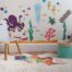 A child's room with decals of ocean animals and ocean plants wall art.