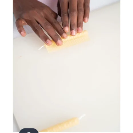 A child's hands rolling a Eco-Kids Honeycomb Beeswax Candle on a white table.