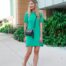 A woman in a green dress standing outside wearing a radiation protection clutch purse.