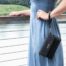 A woman in a blue dress standing outside wearing a radiation protection clutch purse.