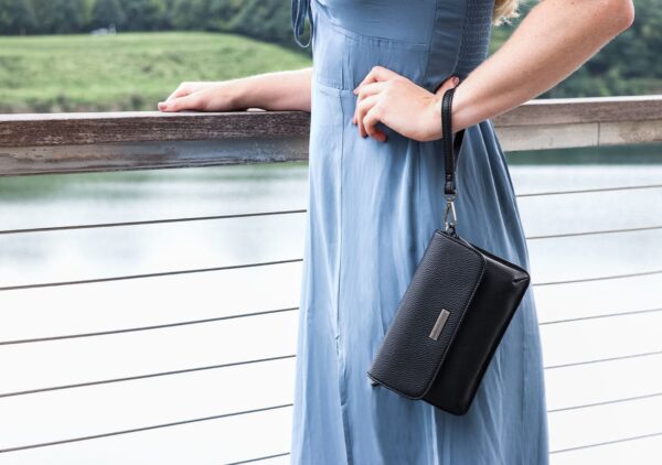 A woman in a blue dress standing outside wearing a radiation protection clutch purse.