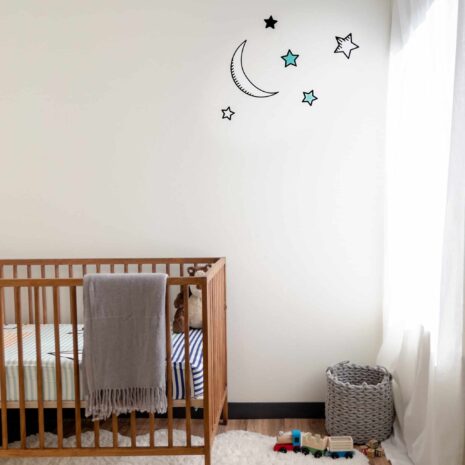 A nursery with a crib and moon and stars wall art decals.