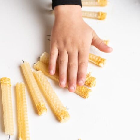 A child's hands rolling a Eco-Kids Honeycomb Beeswax Candle on a white table.